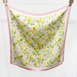 Détail du foulard en soie avec imprimé citron, feuilles vertes et bord rose
