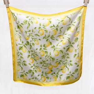 Détail d'un foulard en soie carré avec imprimé citron et bordure jaune en finition satinée