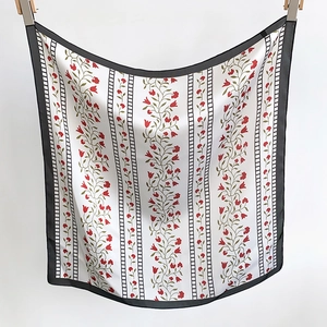 Detailed macro view of the elegant floral satin scarf with black borders and vine patterns