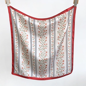 Detail view of white floral silk scarf with red edges and vertical pattern on white background