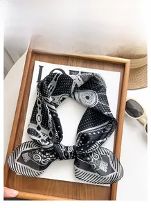 Détail d'un foulard en soie imprimé à pois et motifs ethniques sur plateau en bois