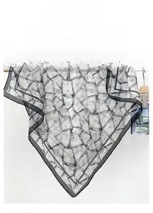 Detailed texture of lightweight sheer silk scarf with modern black geometric print