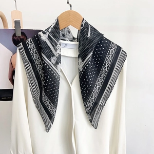 Élégant foulard en soie noir et blanc à motif paisley noué sur un col de chemise blanc
