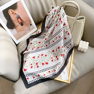 Floral square silk scarf with red blossoms and black border draped on a gold frame