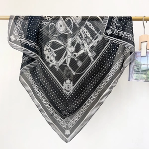 Détail d'un élégant foulard carré en soie noir et blanc aux motifs équestres vintage