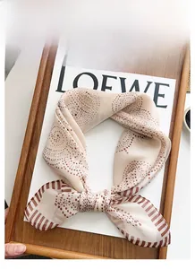 Detail of sheer beige silk scarf featuring elegant brown polka dots and diagonal stripes