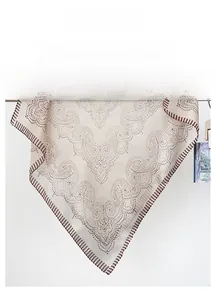 Detail of elegant beige silk scarf featuring brown paisley patterns and striped edges