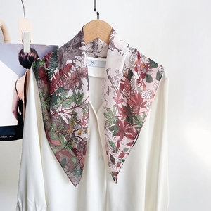 Detail of elegant forest print silk scarf paired with a minimalist white button-down shirt