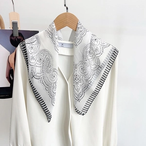 Close-up of black and white polka dot silk scarf with striped edges on wooden hanger