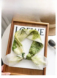 Détail d'un foulard en mousseline légère avec motif de feuilles vertes et texture douce