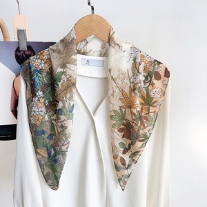 Close-up of floral print silk scarf draped over a white shirt with earth-tone colors