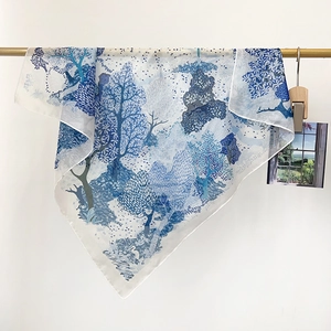 Détail d'un foulard en soie léger avec illustrations de forêt et d'oiseaux bleus