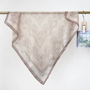 Detailed view of beige paisley chiffon scarf with brown dots hanging on a metal rod