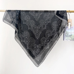 Detail view of lightweight chiffon scarf with elegant paisley patterns and dotted border