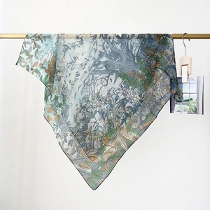 Detail of floral print silk scarf with nature illustrations on a gold rack