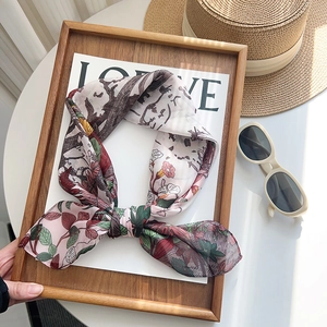 Elegant floral print silk scarf in soft pink with vibrant flower patterns for summer vacation