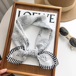 Elegant black and white polka dot silk scarf displayed with sun hat and sunglasses