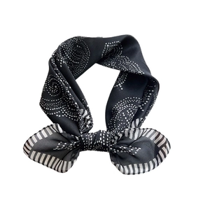 Elegant black and white polka dot silk scarf tied in a classic French style bow knot