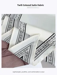 Detailed view of black and white twill satin fabric featuring retro paisley and polka dots