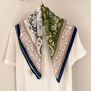 Detail eines Seiden-Halstuchs mit Paisley-Muster an einem weißen Hemd gebunden