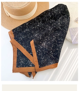 Close-up of black floral cotton scarf with brown border detail on white background