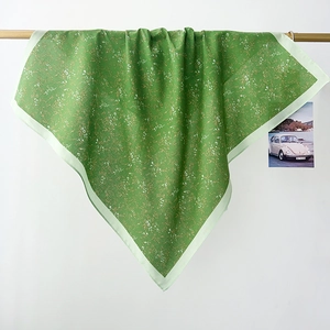 Detailed macro of green floral cotton scarf draped over a wooden rod with folds