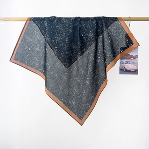 Detail of floral cotton scarf with deep grey pattern and orange borders draped on wood