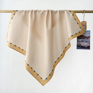 Detail of hanging blue and yellow cotton scarf featuring linear patterns and polka dots