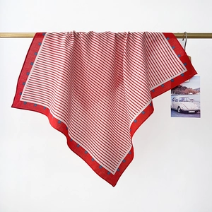 Detail view of cotton neckerchief featuring red stripes and blue polka dot border