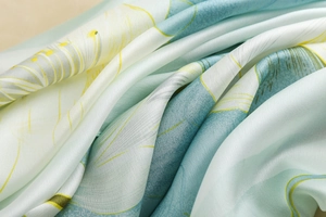 Gros plan sur le tissu d'un foulard en soie avec motifs floraux vert clair et satinés