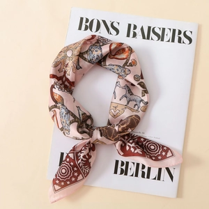 Detailed view of pink silk scarf with giraffe and horse animal print on fashion magazine