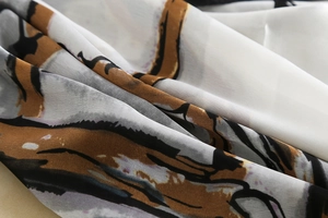 Detailed macro view of sheer silk scarf with abstract dark grey and brown ink patterns