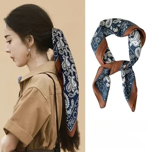 Deep blue paisley satin scarf used as a stylish hair tie accessory for ponytail
