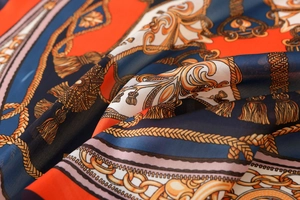 Macro shot of luxurious satin scarf fabric with baroque chain patterns and gold tassels