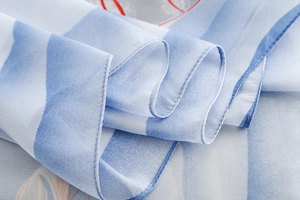 Détail d'écharpe en soie rayée bleu clair montrant les coutures fines et la texture
