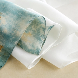 Elegant white silk scarf with blue lotus floral print and soft draped texture