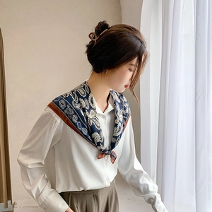 Detail of silk-like paisley square scarf styled as an elegant neck tie for women
