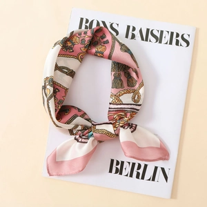 Detail of silk satin scarf with pink gold chain print draped over a fashion magazine
