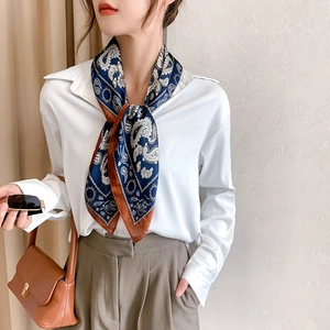 Elegant paisley square scarf with navy and caramel patterns worn over a white blouse