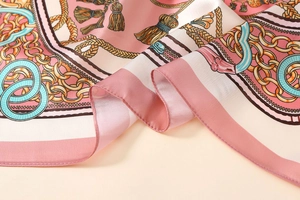 Close-up of silk scarf showing elegant gold chain pattern and smooth satin texture