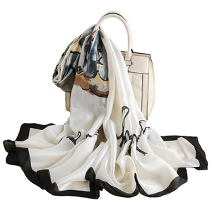 Elegant silk scarf with lotus print and black borders draped on a handbag