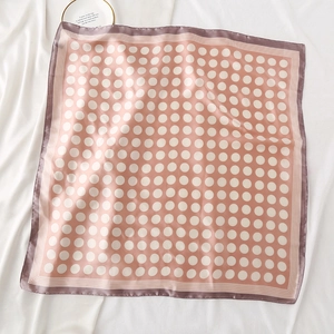 Détail du foulard en soie rose poudré à pois blancs avec bordure contrastée chic