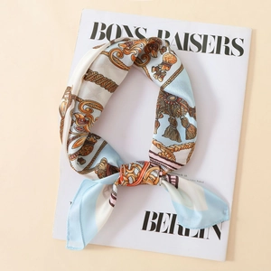 Close-up of a satin silk scarf with vintage Baroque chain patterns and golden tassels