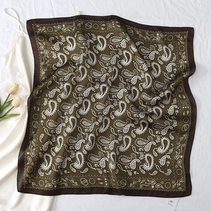 Detailed macro view of olive green paisley silk square scarf on white fabric