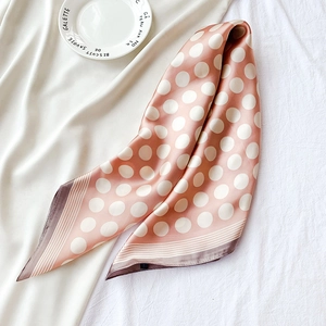 Élégant foulard en satin rose poudré à pois blancs sur un tissu décoratif blanc