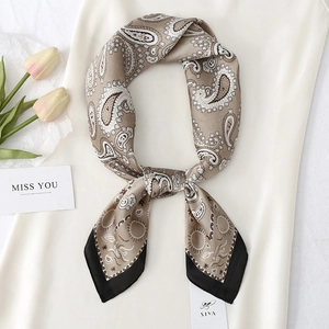Close-up of elegant paisley silk square scarf with khaki pattern and black border trim