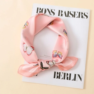 Close-up of lightweight light pink satin scarf with colorful butterfly print and silky texture