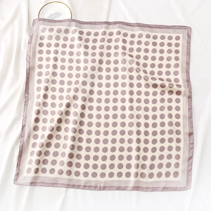 Détail d'un foulard en soie à pois avec bordures rayées sur fond de soie élégant