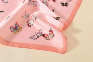Detailed view of pink satin scarf featuring vibrant butterfly prints and silky texture