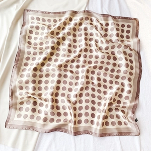 Détail de foulard en soie à pois avec base crème, pois marron et bordure à rayures fines